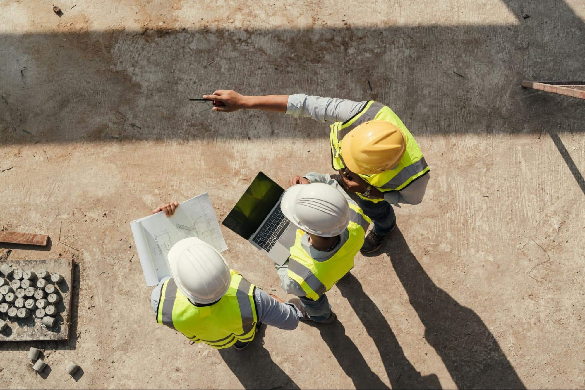 Construction workers at a job site and looking at a laptop together