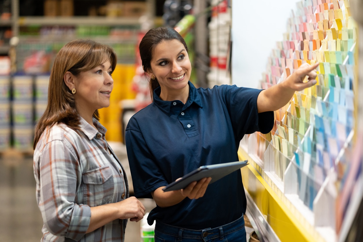 A salesperson helping a customer choose a paint color at a home improvement store