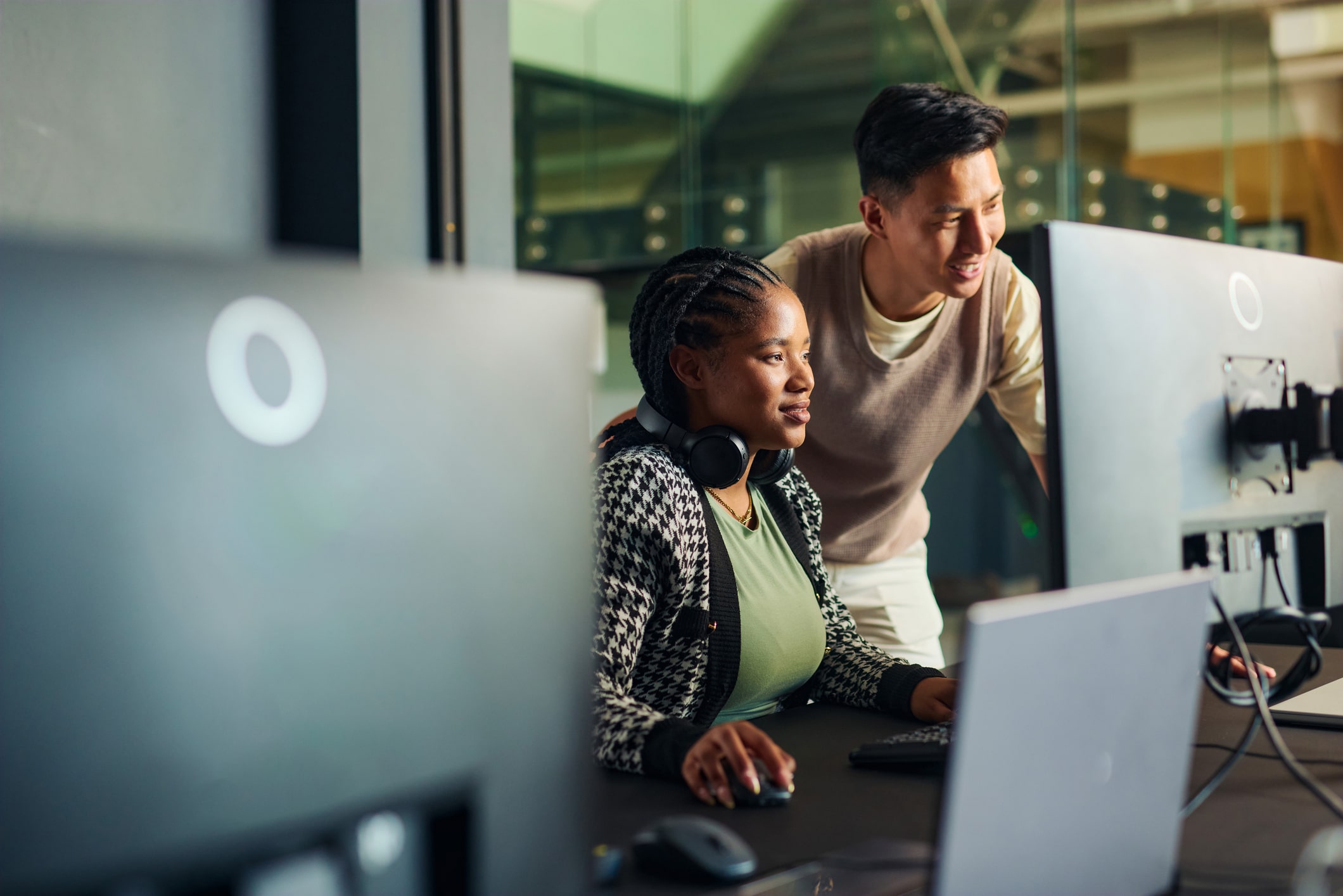 Software engineers collaborating on a project, analyzing code on computer monitors in office