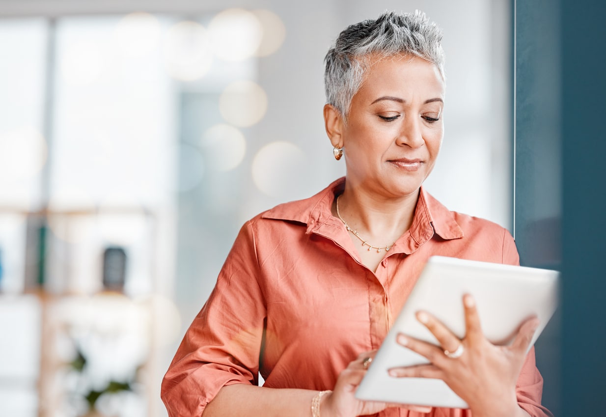 Senior businesswoman using a tablet in a bright office environment.