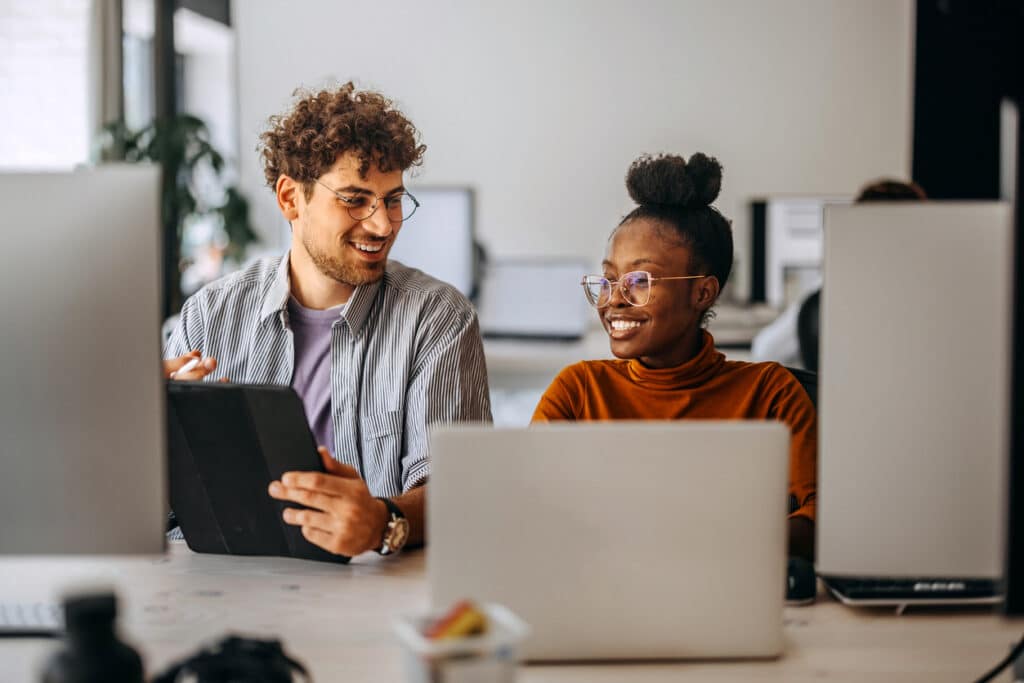 Two young colleagues sitting at a table and working together in a modern office.