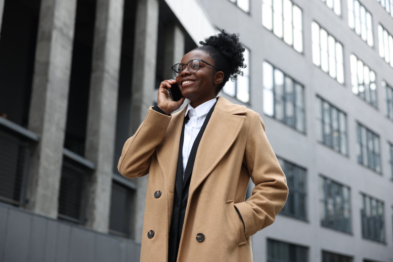 Woman speaking confidently on a mobile phone and walking down the street on a bright day