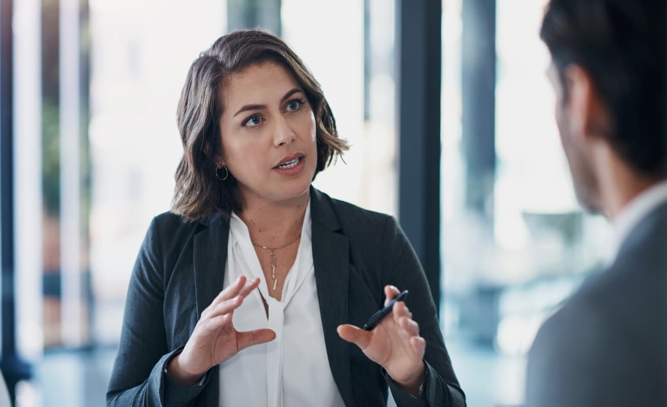 A businesswoman speaks to an unseen employee in an office setting.