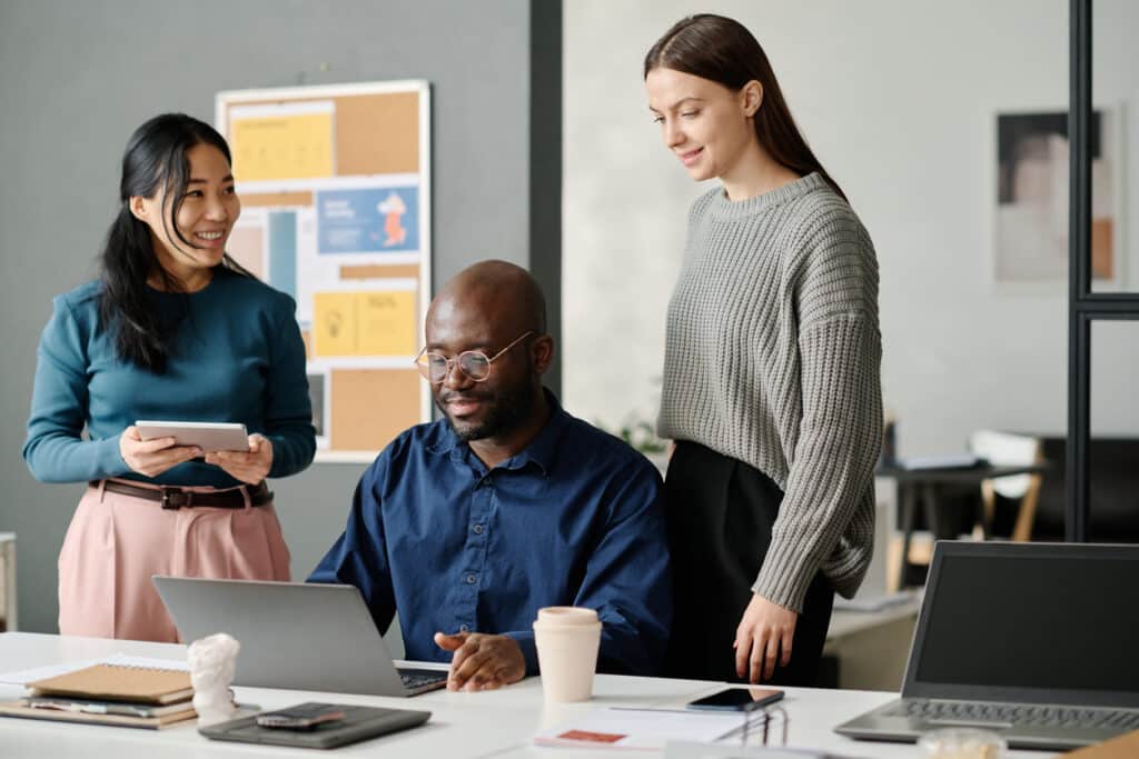 Ethnically diverse group of three working together on a laptop.