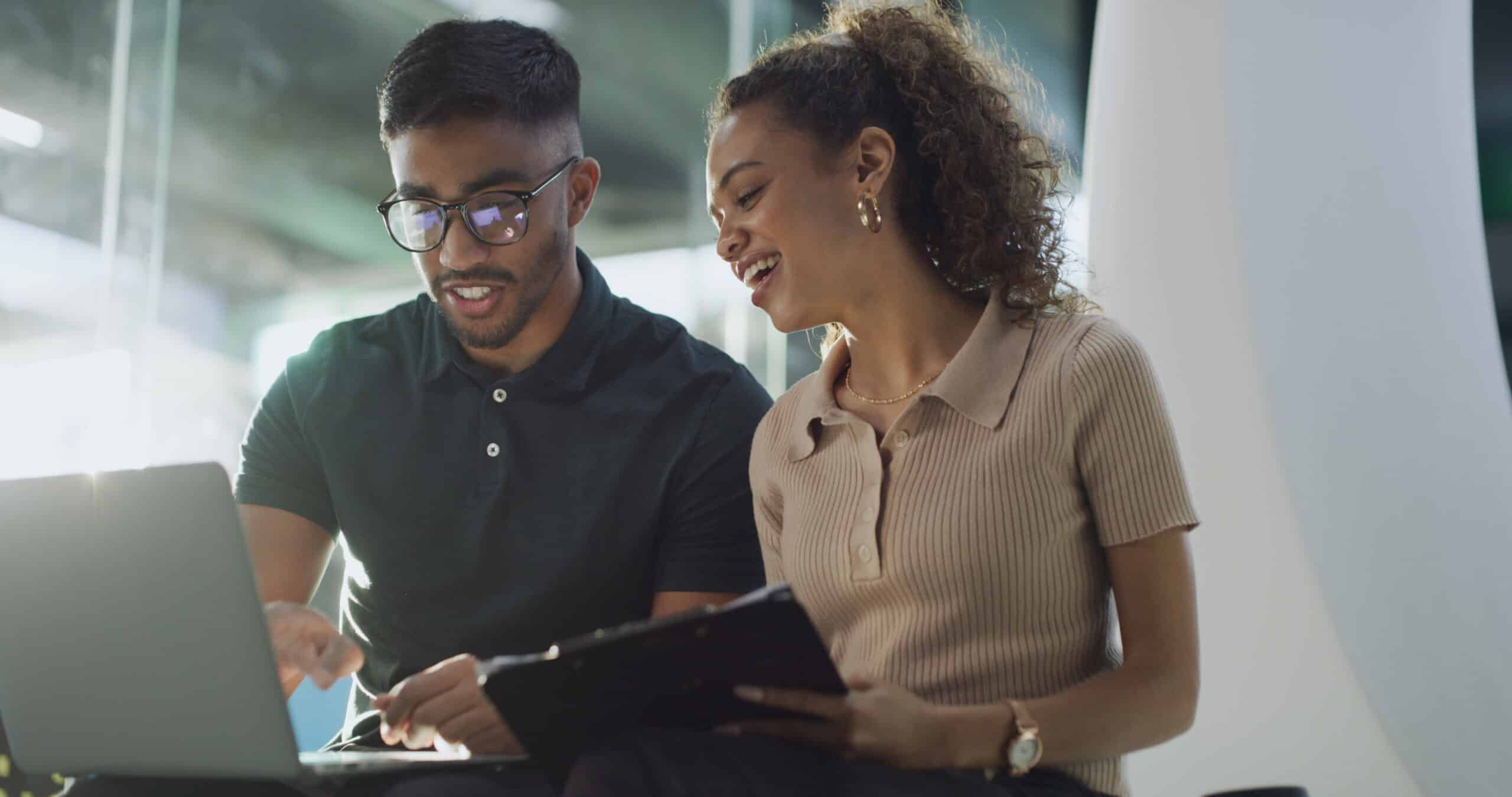 People smiling and pointing at a laptop screen in an office setting