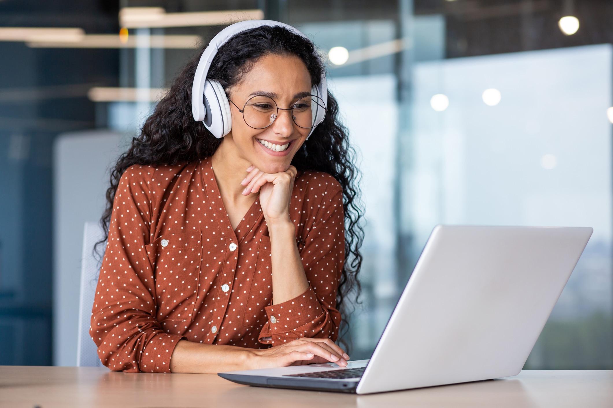 Person in headphones working with laptop inside office at workplace